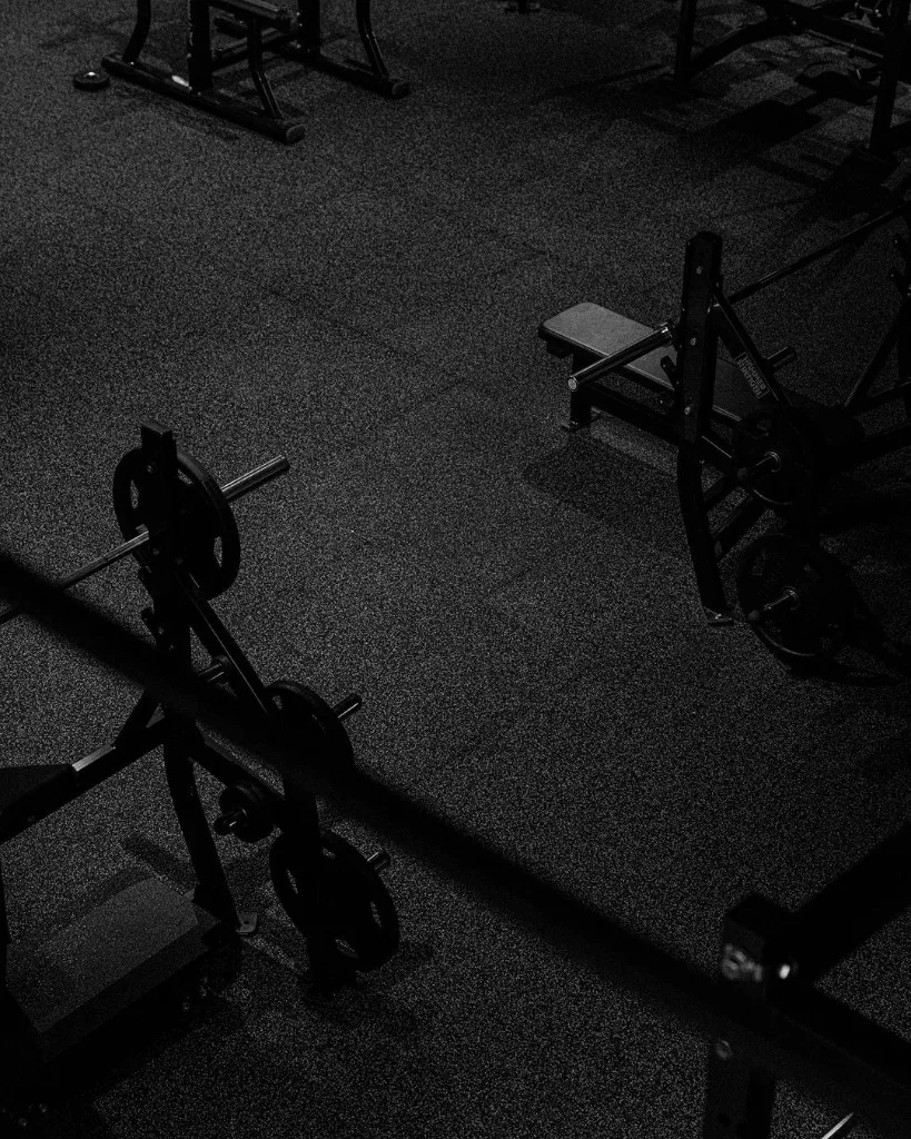 an empty gym floor before opening, benches and loaded barbells in low light